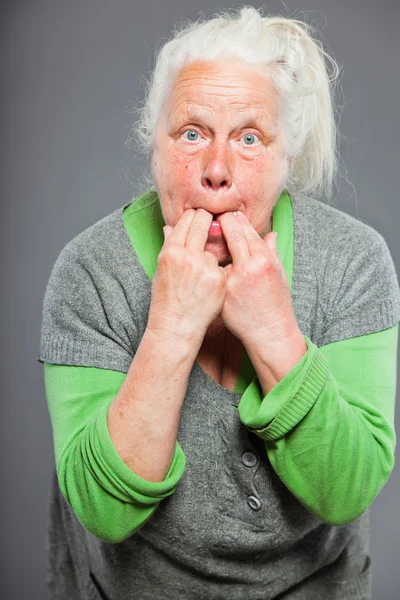 Senior vrouw fluiten met haar vingers. handelend jonge. studio opname geïsoleerd op grijze achtergrond. — Stockfoto