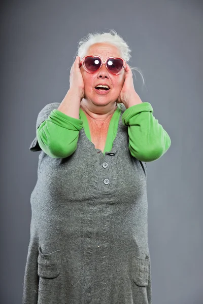 Seniorin mit Sonnenbrille und ausdrucksstarkem Gesicht. Lustig. Studioaufnahme isoliert auf grauem Hintergrund. — Stockfoto