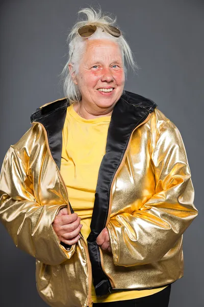 Cool femme âgée portant une veste dorée. Cheveux longs et gris. Lunettes de soleil. Prise de vue. Isolé . — Photo