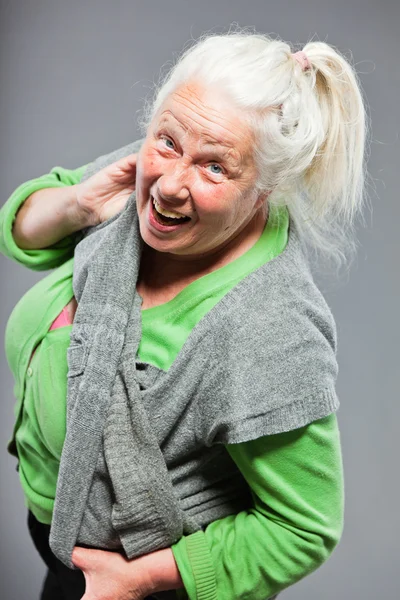 Roliga uttrycksfulla senior kvinna. agerar unga. Studio skott isolerade på grå bakgrund. — Stockfoto