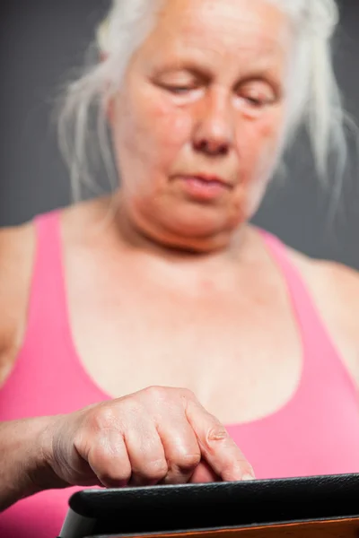 Mujer mayor sosteniendo tableta de pelo largo gris. Grabado en estudio. Aislado sobre fondo gris . — Foto de Stock