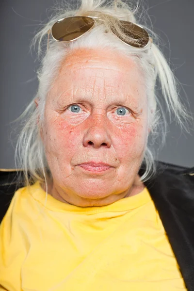 Cool senior woman wearing golden jacket. Long grey hair. Sunglasses. Studio shot. Isolated. — Stock Photo, Image
