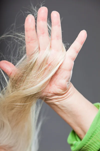 Zbliżenie dłoni starszych kobiety w włosy. wyśmienity. na szarym tle. — Zdjęcie stockowe
