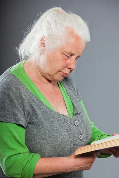 Senior woman white grey hair reading a book. Studio shot isolated on grey background. — Stock Photo, Image