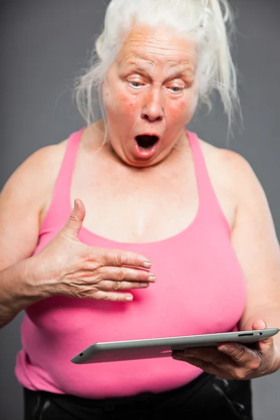 Femme âgée tenant un comprimé longs cheveux gris. Prise de vue. Isolé sur fond gris . — Photo