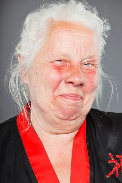 Старшая женщина с длинными седыми волосами в черно-красном кимоно. Съемка изолирована на сером фоне . — стоковое фото