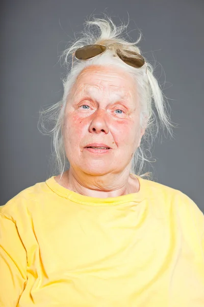 Cool hip senior femme avec des lunettes de soleil et de longs cheveux gris. Visage expressif. Studio tourné isolé sur gris . — Photo