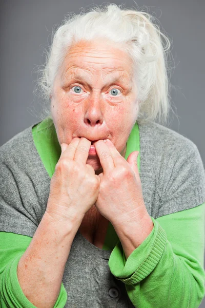 年配の女性は彼女の指で口笛を吹きます。若い演技。スタジオ撮影に分離の灰色の背景. — ストック写真