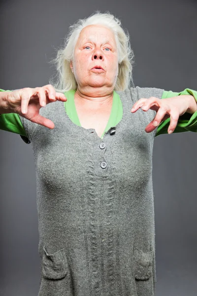 Senior woman white grey hair doing spiritual poses. Expressive face and hands. Studio shot isolated on grey background. — Stock Photo, Image