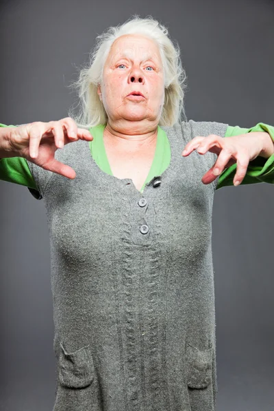 Mulher sênior cabelos brancos cinza fazendo poses espirituais. Cara e mãos expressivas. Estúdio tiro isolado em fundo cinza . — Fotografia de Stock