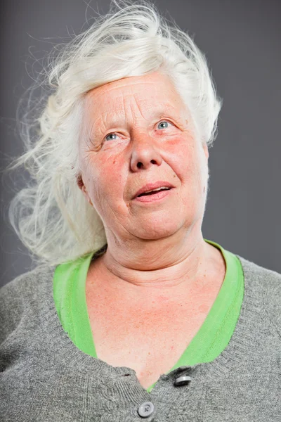 Студійний портрет щасливої старшої жінки з довгим волоссям на вітрі. Студійний знімок ізольовано на сірому фоні . — стокове фото