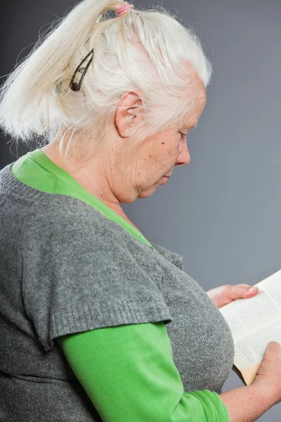 Mulher sênior cabelos brancos cinzentos lendo um livro. Estúdio tiro isolado em fundo cinza . — Fotografia de Stock