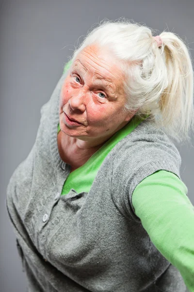 Roliga uttrycksfulla senior kvinna. agerar unga. Studio skott isolerade på grå bakgrund. — Stockfoto