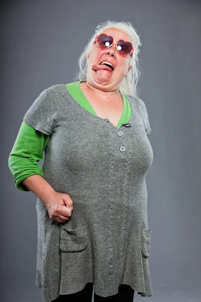 Äldre kvinna bär solglasögon med uttrycksfullt ansikte. Rolig. Studio skott isolerade på grå bakgrund. — Stockfoto