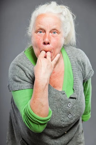 Mujer mayor silbando con los dedos. Actuando joven. Estudio plano aislado sobre fondo gris . — Foto de Stock