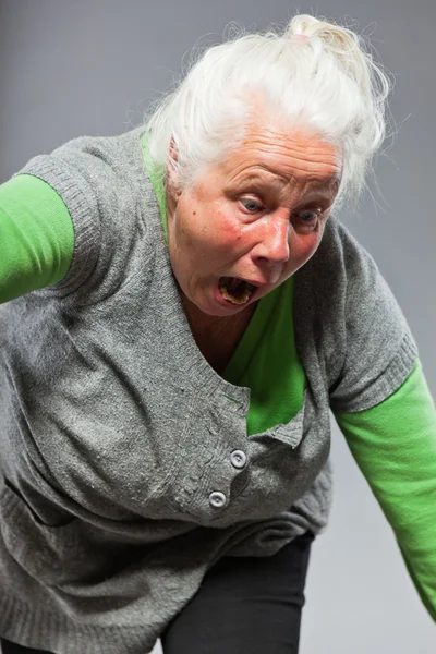 재미 있는 표현 고위 여자. 젊은 행동. 스튜디오 촬영에 고립 된 회색 배경. — 스톡 사진