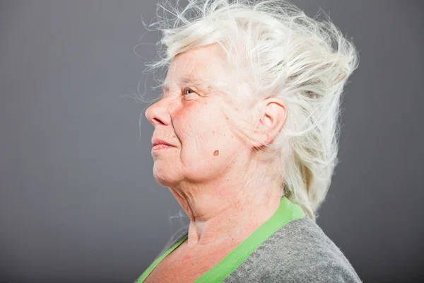 Studio ritratto di felice donna anziana con i capelli lunghi nel vento. Studio girato isolato su sfondo grigio . — Foto Stock