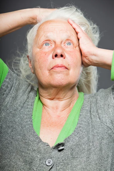 Senior mulher de mãos dadas no cabelo. Um olhar espiritual. Estúdio tiro isolado em fundo cinza . — Fotografia de Stock
