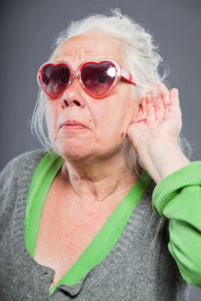 Äldre kvinna med solglasögon döva. dålig hörsel. höft och sval sett. Studio skott. isolerad på grå bakgrund. — Stockfoto