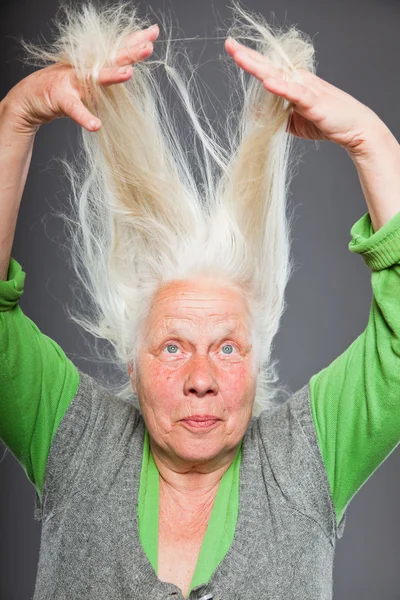 Mujer mayor cogida de la mano en el pelo. Mirada espiritual. Estudio plano aislado sobre fondo gris . —  Fotos de Stock