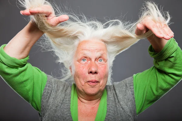 Senior kvinna med händerna i hennes hår. andligt sett. Studio skott isolerade på grå bakgrund. — Stockfoto