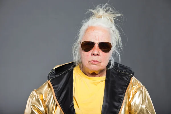 Крутая пожилая женщина в золотой куртке. Длинные седые волосы Солнечные очки. Студийный снимок Isolated . — стоковое фото
