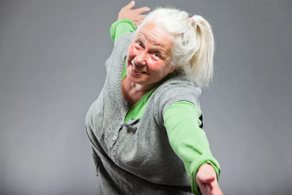 Divertente donna anziana espressiva. Si comporta da giovane. Studio girato isolato su sfondo grigio . — Foto Stock