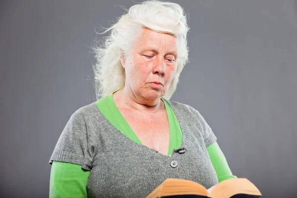 Stúdió portré idősebb nő, egy könyvet olvas. stúdió felvétel elszigetelt a szürke háttér. — Stock Fotó