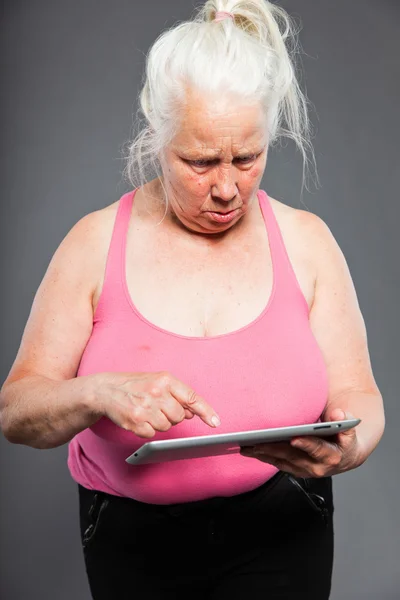 Mujer mayor sosteniendo tableta de pelo largo gris. Grabado en estudio. Aislado sobre fondo gris . —  Fotos de Stock