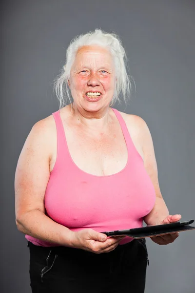 Senior woman holding tablet long grey hair. Studio shot. Isolated on grey background. — Stock Photo, Image
