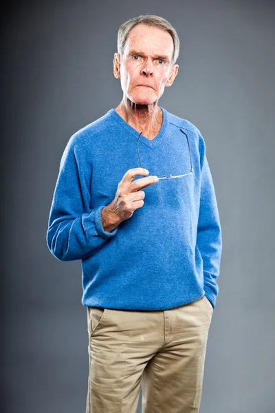 Homem idoso expressivo e bonito contra a parede cinzenta. Engraçado e característico. Bem vestida. Camisola azul. Estúdio . — Fotografia de Stock