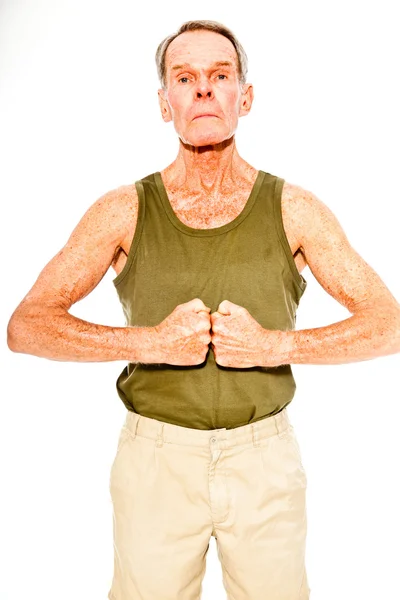 Athletisch gut aussehender älterer Herr lässig sommerlich gekleidet vor weißer Wand. Er trainiert seine Muskeln. glücklich, lustig und charakteristisch. Vereinzelt. Studioaufnahme. — Stockfoto
