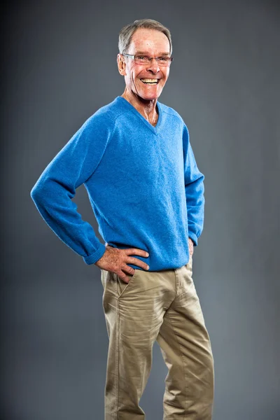 Uttrycksfulla snygg senior mannen mot grå vägg. rolig och karakteristiska. välklädd. blå tröja. Studio skott. — Stockfoto