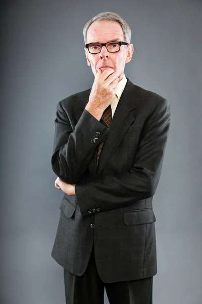 Выразительный симпатичный мужчина в темном костюме против серой стены. В очках. Забавно и характерно. Хорошо одет. Снимок студии . — стоковое фото