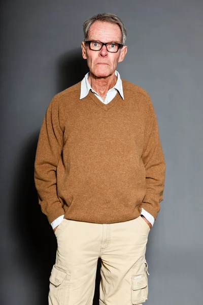 Expressieve goed uitziende senior man dragen van een bril tegen grijs muur. grappig en karakteristiek. goed gekleed. studio opname. — Stockfoto