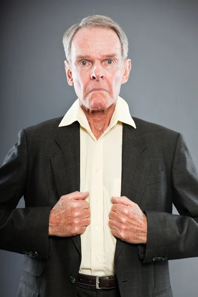 Espressivo bell'uomo anziano in abito scuro contro il muro grigio. Divertente e caratteristico. Ben vestita. Studio girato . — Foto Stock