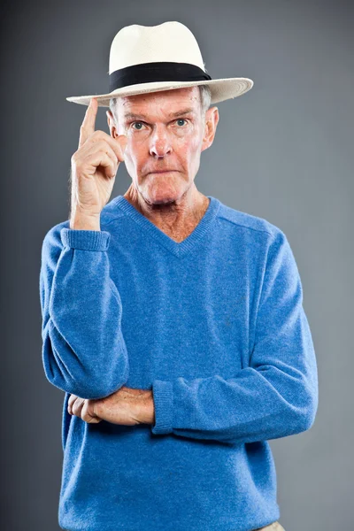 Expresivní dobře vypadající starší muž proti šedé zdi. klobouk. zábavný a charakteristické. dobře oblečený. modrý svetr. Studio záběr. — Stock fotografie