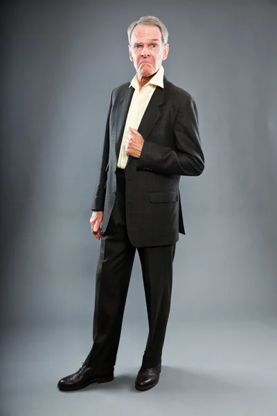 表現力豊かな良い探しシニア スーツの男暗い灰色の壁に対して。面白いと特性。よく服を着てください。スタジオ撮影. — ストック写真
