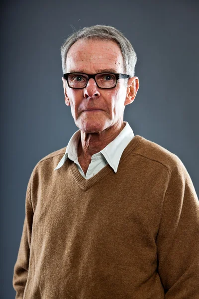 Espressivo bell'uomo anziano con gli occhiali contro il muro grigio. Divertente e caratteristico. Ben vestita. Studio girato . — Foto Stock