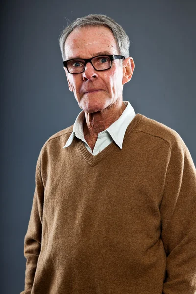 Espressivo bell'uomo anziano con gli occhiali contro il muro grigio. Divertente e caratteristico. Ben vestita. Studio girato . — Foto Stock