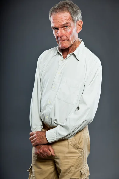 Výrazně pohledný starší muž u šedé zdi. Vtipné a charakteristické. Dobře oblečená. Studio shot. — Stock fotografie
