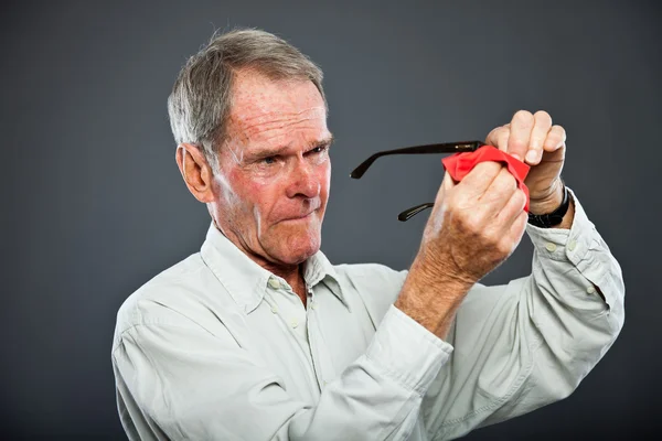 Homem idoso expressivo e bonito contra a parede cinzenta. A limpar os óculos. Engraçado e característico. Bem vestida. Estúdio . — Fotografia de Stock