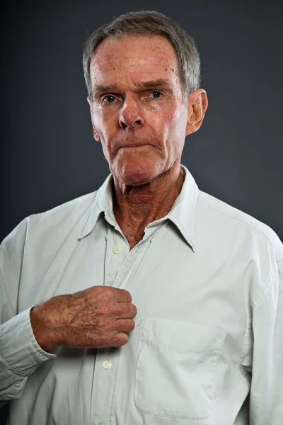 Ausdrucksstarker gut aussehender älterer Herr vor grauer Wand. Witzig und charakteristisch. Gut angezogen. Studioaufnahme. — Stockfoto