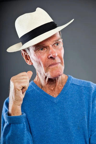 Wyraziste, dobrze wyglądający starszy człowiek ścianę szary. kapeluszu. zabawny i charakterystyczne. dobrze ubrany. niebieski sweter. łapka. — Zdjęcie stockowe