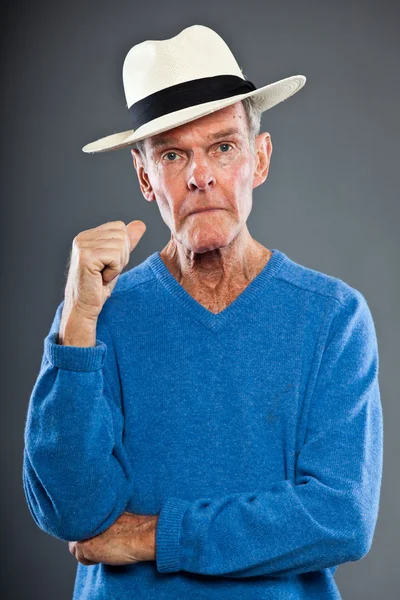Uttrycksfulla snygg senior mannen mot grå vägg. bära hatt. rolig och karakteristiska. välklädd. blå tröja. Studio skott. — Stockfoto