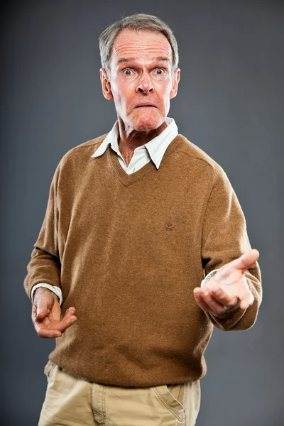 Expressieve goed uitziende senior man tegen grijze muur. Grappig en karakteristiek. Goed gekleed. Studioshoot. — Stockfoto
