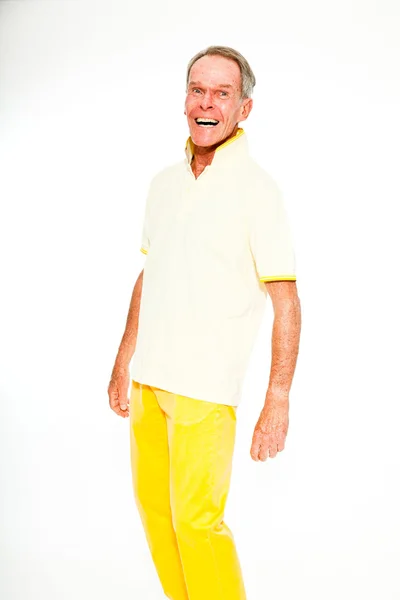 Выразительный, хорошо выглядящий пожилой мужчина, одетый в летнее платье, прислонившееся к белой стене. Счастливый, забавный и характерный. Изолирована. Снимок студии . — стоковое фото