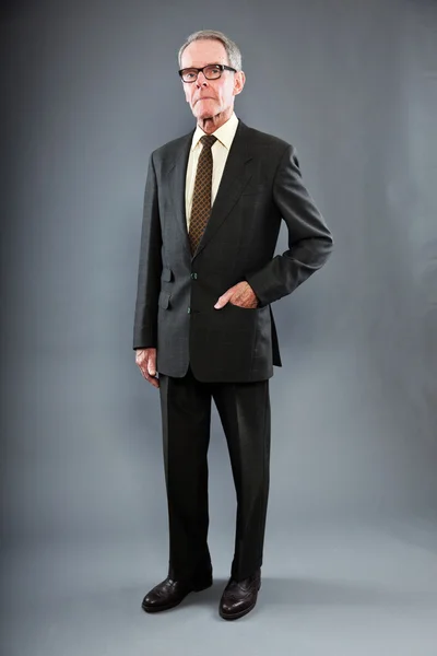 表現力豊かな良い探しシニア スーツの男暗い灰色の壁に対して。メガネを着用します。面白いと特性。よく服を着てください。スタジオ撮影. — ストック写真