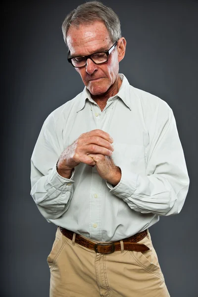 Homem sênior bem parecido expressivo com óculos contra a parede cinza. Mãos a rezar. Espiritual e característico. Bem vestida. Estúdio . — Fotografia de Stock
