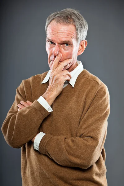 Expressive good looking senior man against grey wall. Funny and characteristic. Well dressed. Studio shot. Stock Picture